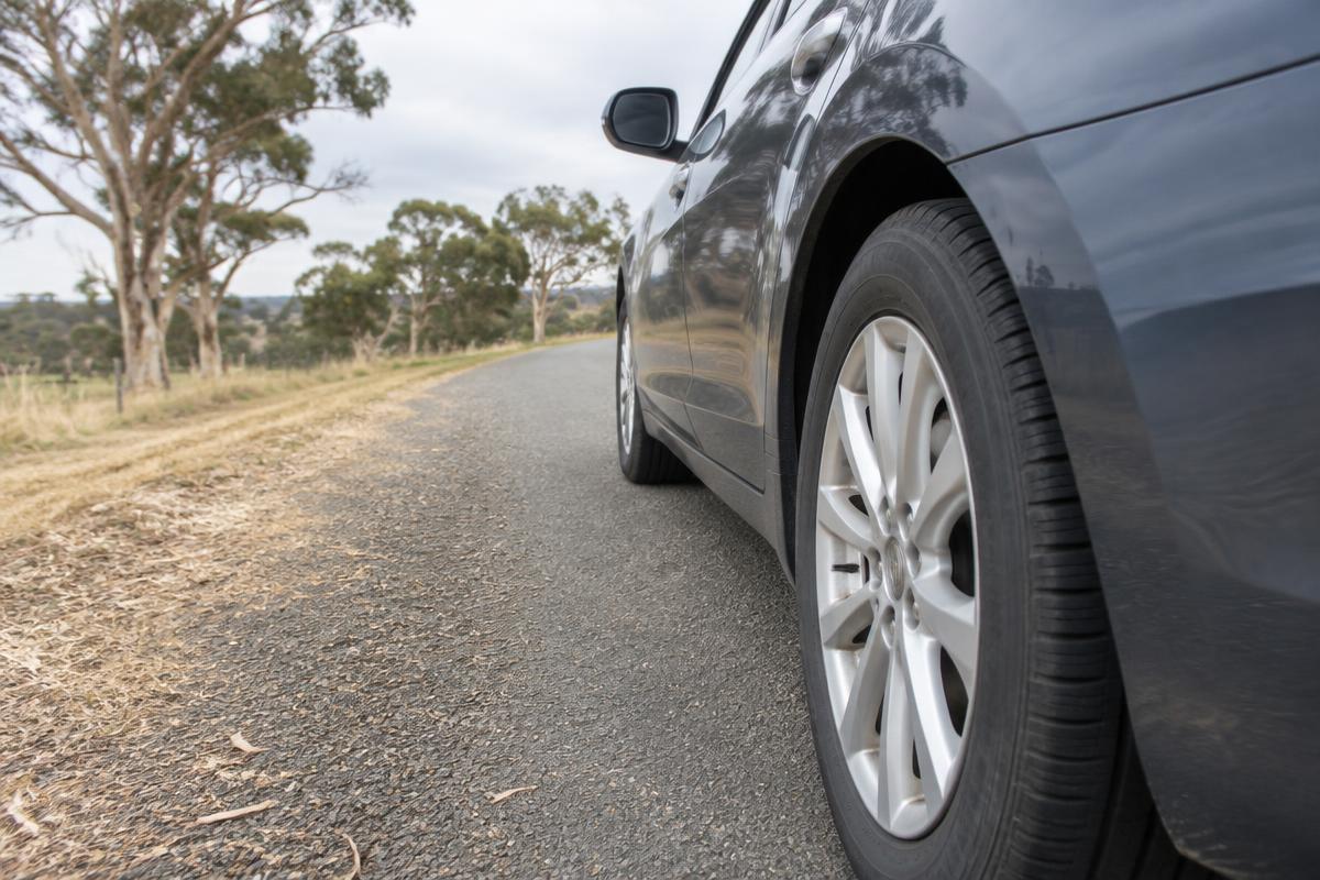 Close-up of the rear tyre on a dark grey family sedan in a studio.