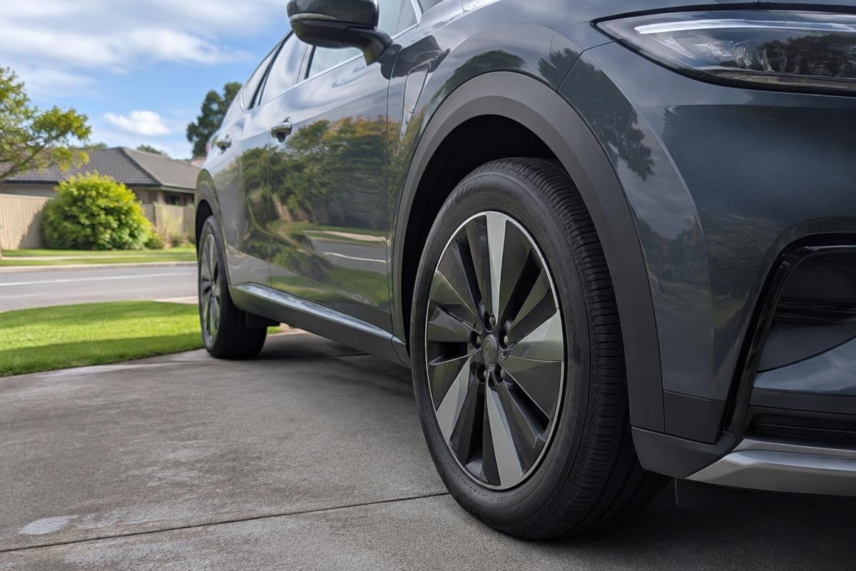 Close-up of the front tyre on a dark blue electric SUV in a studio.