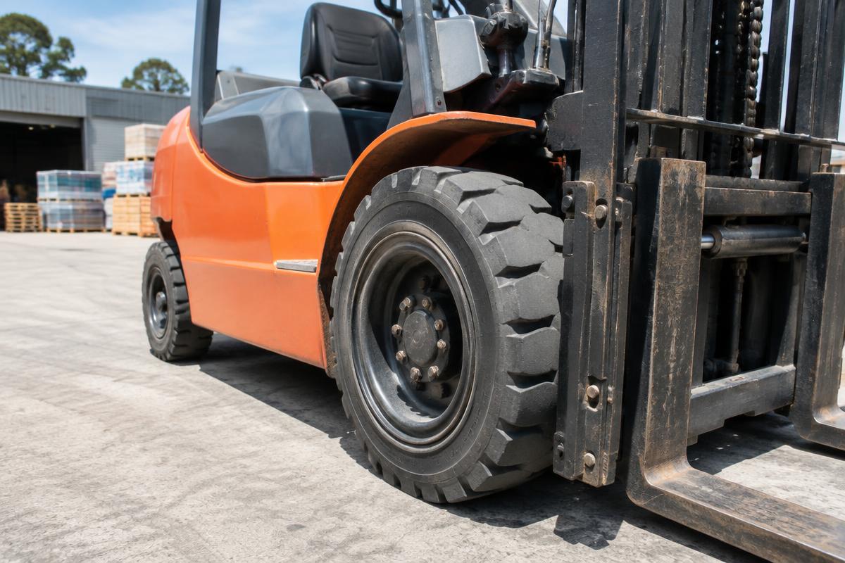 Close-up of the solid industrial tyre on an orange forklift.
