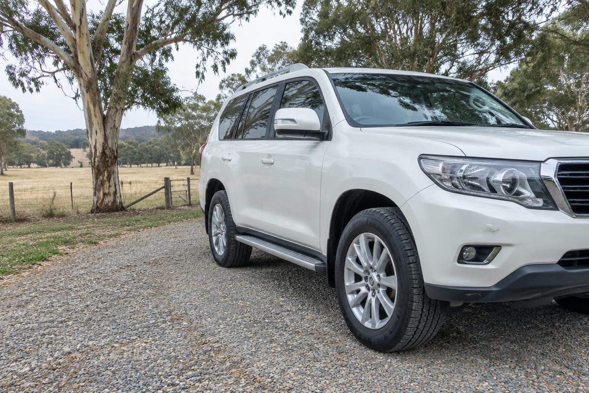 Close-up of the rear highway-terrain tyre on a white family SUV in a studio.